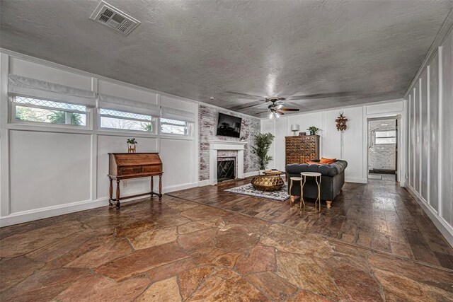 living room featuring a wealth of natural light, visible vents, ceiling fan, and stone finish flooring