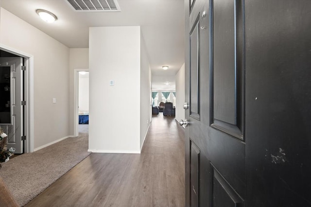 hall featuring wood finished floors, visible vents, and baseboards