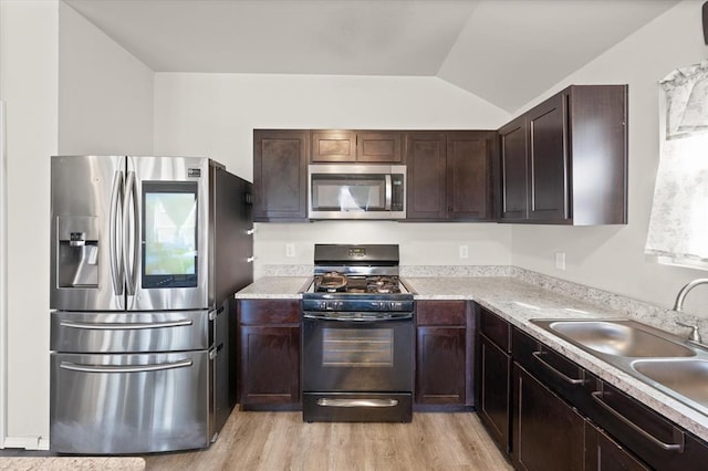 kitchen with light wood finished floors, a sink, stainless steel appliances, dark brown cabinetry, and light countertops