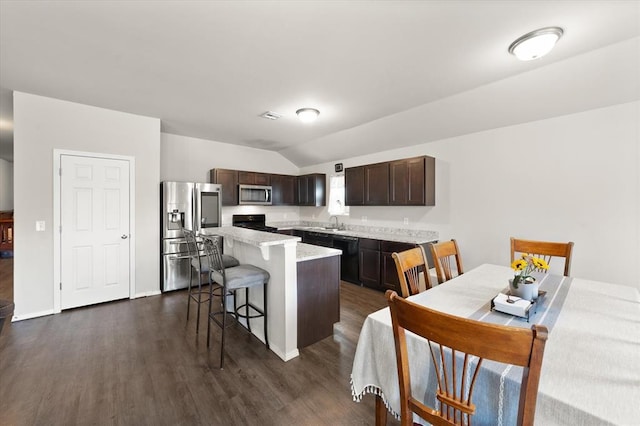 kitchen featuring a breakfast bar, dark wood finished floors, stainless steel appliances, dark brown cabinets, and a center island