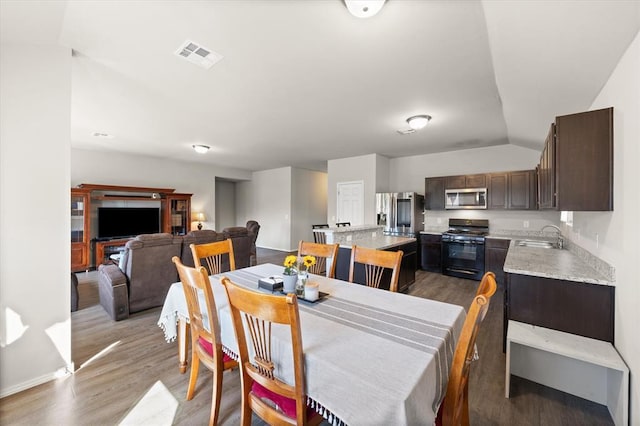 dining area with lofted ceiling, wood finished floors, and visible vents