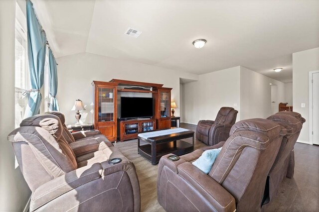 living room featuring vaulted ceiling, visible vents, and wood finished floors