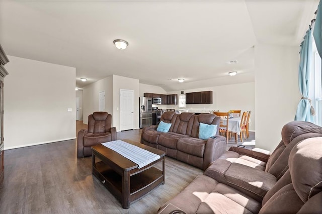 living room featuring lofted ceiling, baseboards, and wood finished floors