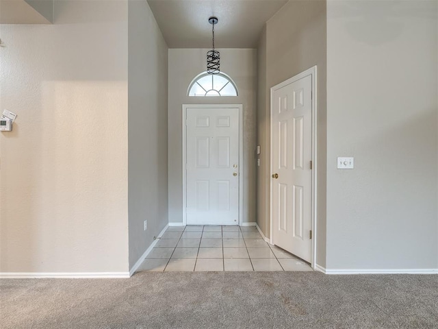 entrance foyer featuring light tile patterned flooring, light colored carpet, and baseboards