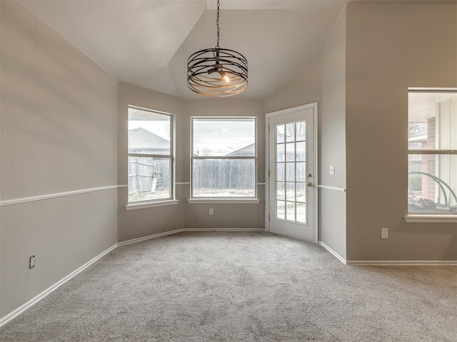 carpeted spare room with vaulted ceiling, baseboards, and a chandelier