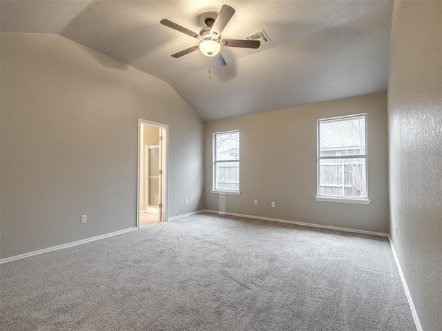 carpeted empty room with visible vents, lofted ceiling, baseboards, and a ceiling fan