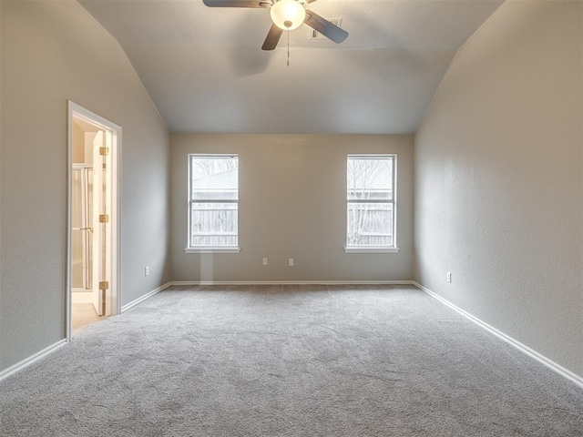 carpeted spare room with vaulted ceiling, a textured wall, baseboards, and ceiling fan