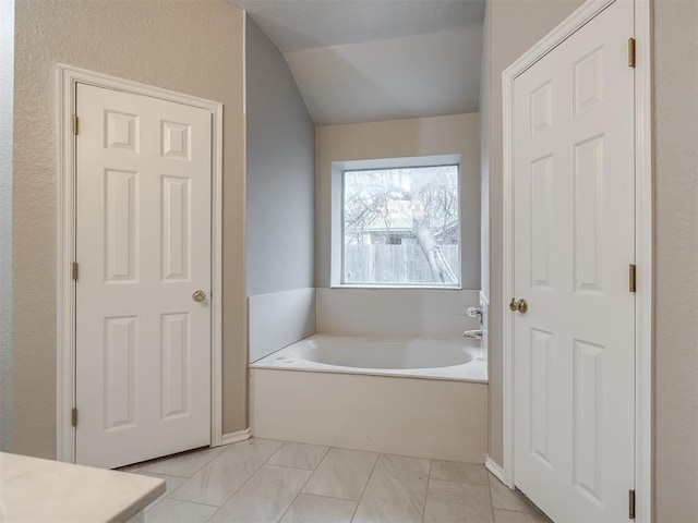 bathroom featuring tile patterned floors, lofted ceiling, and a bath