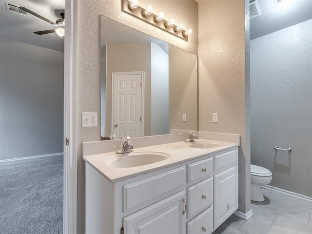 full bathroom with double vanity, toilet, ceiling fan, and a sink