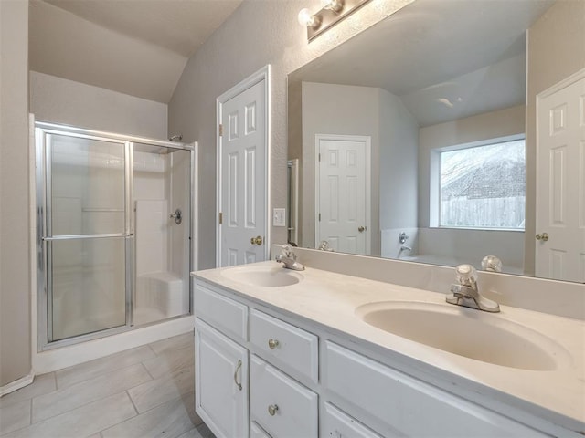 bathroom featuring a sink, lofted ceiling, and a stall shower
