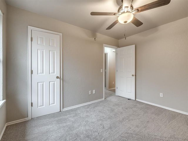 unfurnished bedroom with carpet flooring, a ceiling fan, and baseboards
