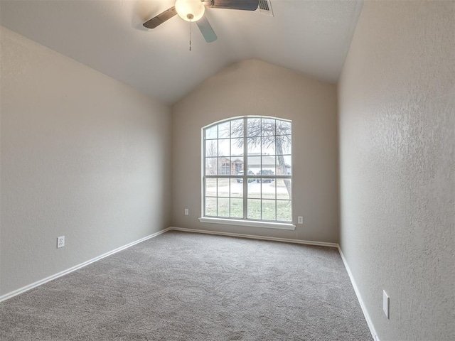 carpeted empty room with vaulted ceiling, a textured wall, baseboards, and ceiling fan