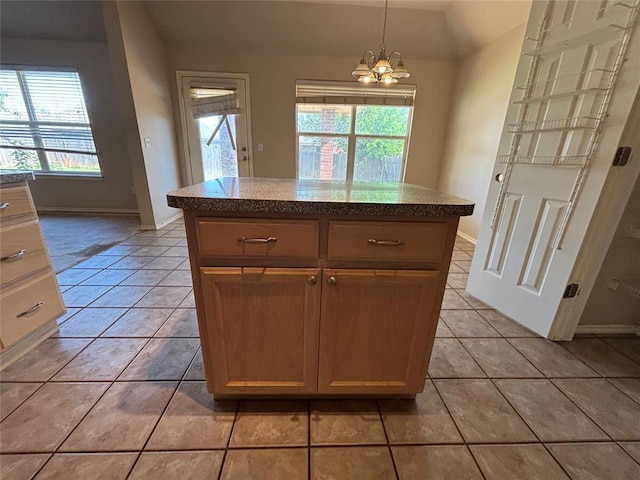kitchen with light tile patterned flooring, an inviting chandelier, hanging light fixtures, a center island, and baseboards