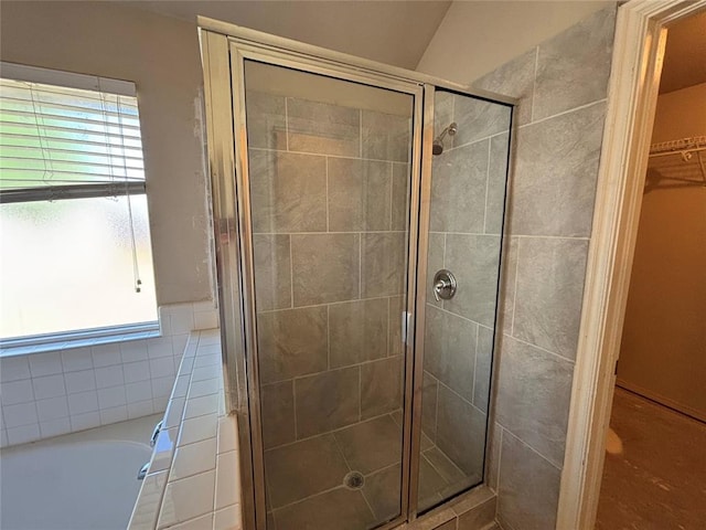 full bathroom featuring a shower stall, a garden tub, and a spacious closet