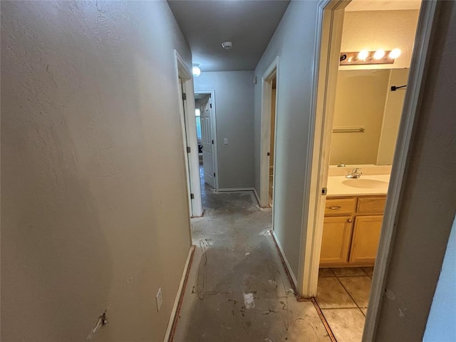 hall with a sink and baseboards