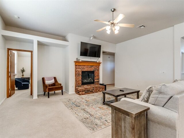 living area featuring visible vents, baseboards, a brick fireplace, ceiling fan, and light colored carpet