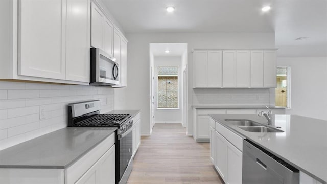 5502 Windstone Ln, Norman, OK 73072 - kitchen featuring stainless steel appliances, light wood-style flooring, backsplash, white cabinets, and recessed lighting