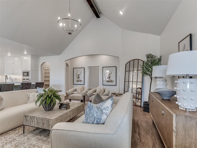 living room with beam ceiling, wood finished floors, high vaulted ceiling, arched walkways, and a chandelier