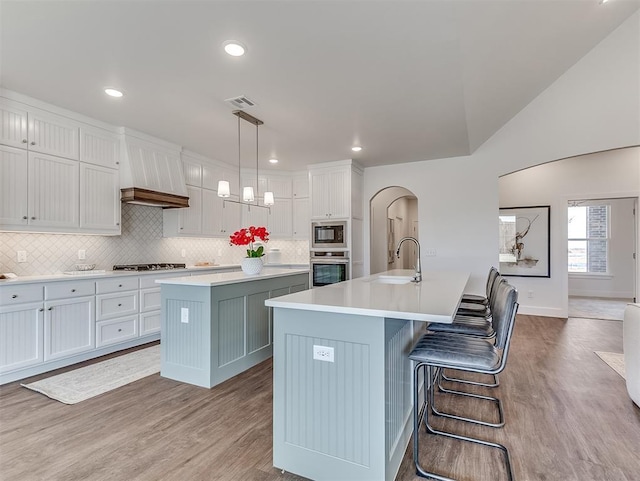 kitchen featuring oven, a center island with sink, built in microwave, a sink, and recessed lighting