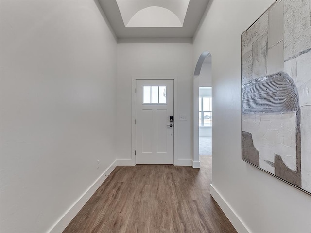 entrance foyer featuring arched walkways, wood finished floors, and baseboards
