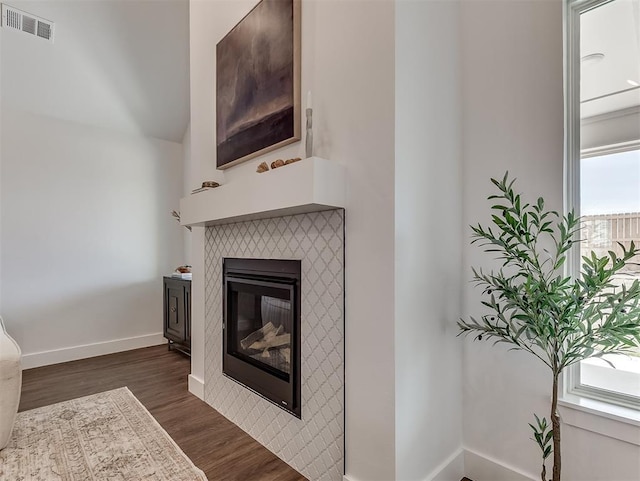 unfurnished living room with dark wood-type flooring, a tile fireplace, and baseboards