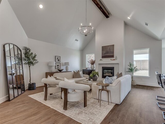 living area with high vaulted ceiling, beam ceiling, a chandelier, wood finished floors, and baseboards