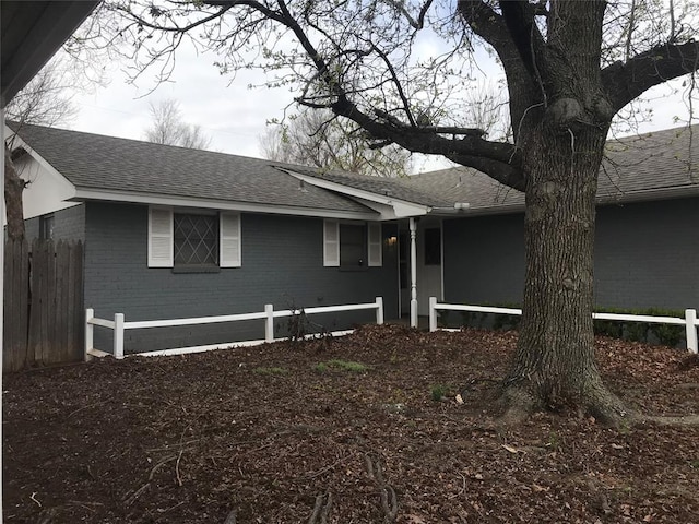 1310 SW 77th Ter, Oklahoma City, OK 73159 - view of front of house featuring brick siding, roof with shingles, and fence
