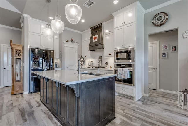 1624 NE 32nd St, Moore, OK 73160 - kitchen featuring stainless steel appliances, ornamental molding, white cabinetry, light countertops, and a kitchen island with sink