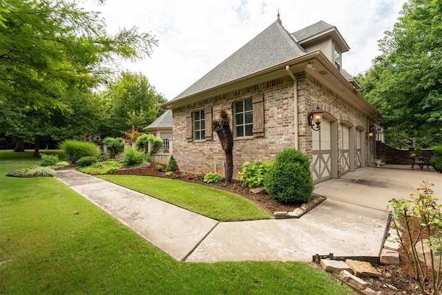 1514 Duxsford Ct, Edmond, OK 73034 - view of property exterior featuring driveway, a yard, a garage, a shingled roof, and brick siding