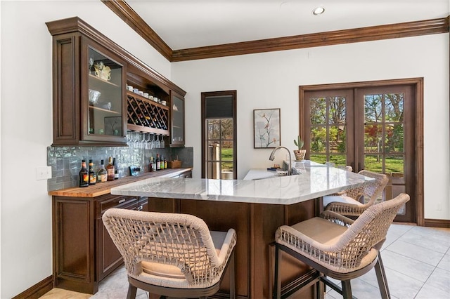 1514 Duxsford Ct, Edmond, OK 73034 - indoor wet bar with backsplash, crown molding, french doors, and light tile patterned flooring