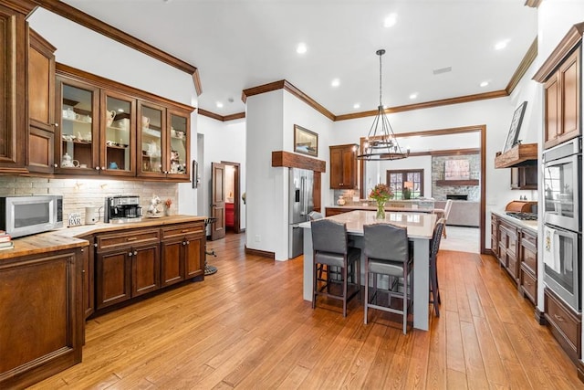 1514 Duxsford Ct, Edmond, OK 73034 - kitchen with appliances with stainless steel finishes, light countertops, decorative backsplash, crown molding, and light wood finished floors