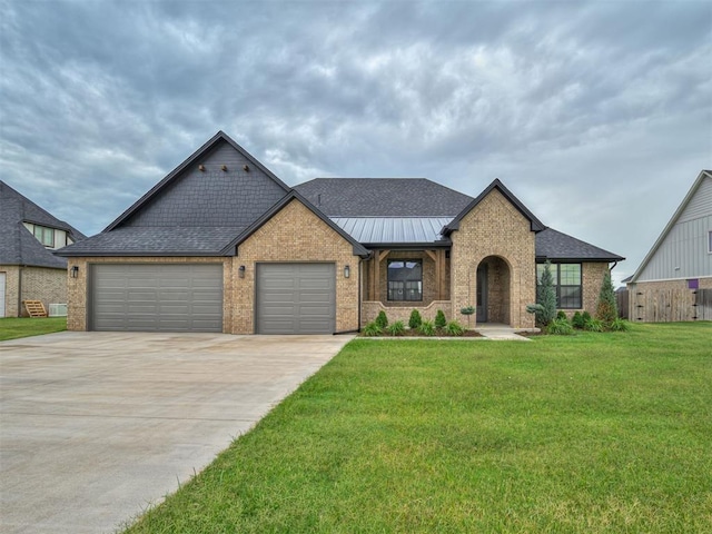 77 Orchid Ct, Piedmont, OK 73078 - view of front of house with brick siding, an attached garage, driveway, a front yard, and a standing seam roof