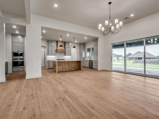 77 Orchid Ct, Piedmont, OK 73078 - kitchen with appliances with stainless steel finishes, gray cabinetry, custom range hood, light countertops, and open floor plan