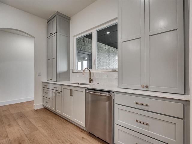 77 Orchid Ct, Piedmont, OK 73078 - kitchen with stainless steel dishwasher, arched walkways, gray cabinetry, light countertops, and light wood finished floors