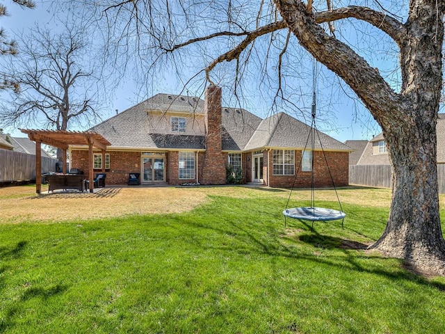rear view of property featuring a lawn, a pergola, brick siding, and a fenced backyard