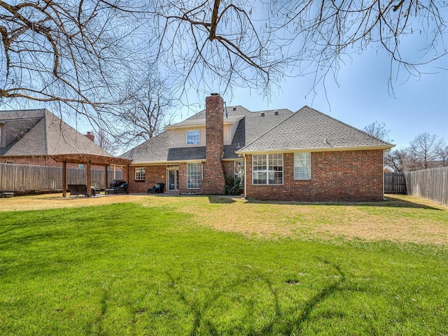 back of house with a yard, a fenced backyard, and brick siding