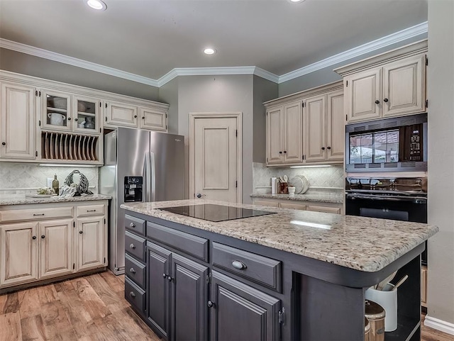 kitchen featuring tasteful backsplash, a center island, black appliances, and light wood-style flooring