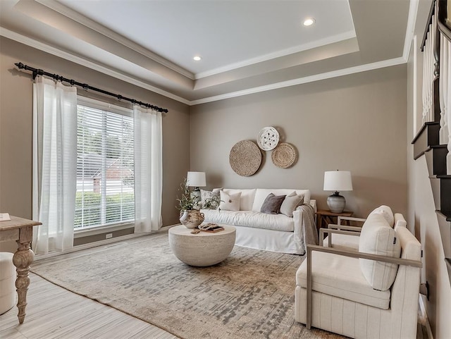 living room with recessed lighting, wood finished floors, crown molding, and a tray ceiling