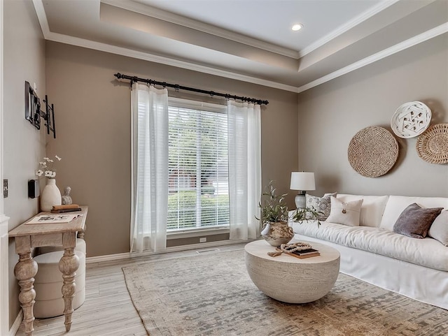 living area with wood finished floors, ornamental molding, baseboards, visible vents, and a tray ceiling