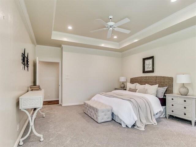 bedroom with crown molding, a ceiling fan, light carpet, and a tray ceiling