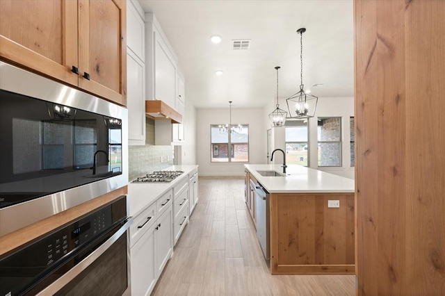 11713 NW 105th St, Yukon, OK 73099 - kitchen with a sink, a chandelier, stainless steel appliances, tasteful backsplash, and light countertops