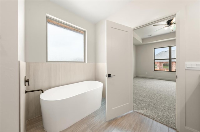 11713 NW 105th St, Yukon, OK 73099 - full bath with a freestanding tub, a ceiling fan, wainscoting, and wood finished floors