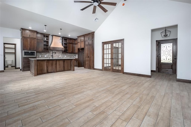 1431 County Road 2977, Blanchard, OK 73010 - kitchen featuring open shelves, custom range hood, open floor plan, stainless steel microwave, and high vaulted ceiling