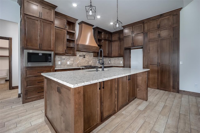 1431 County Road 2977, Blanchard, OK 73010 - kitchen featuring stainless steel microwave, premium range hood, open shelves, backsplash, and light wood-style floors