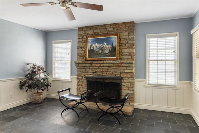1716 Westminster Pl, Nichols Hills, OK 73120 - living area with wainscoting, ceiling fan, dark tile patterned floors, and a stone fireplace