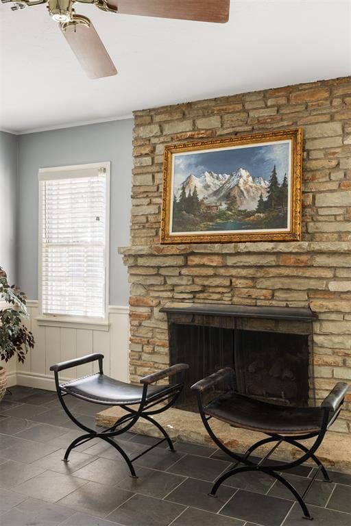 1716 Westminster Pl, Nichols Hills, OK 73120 - sitting room with a stone fireplace, a wainscoted wall, stone tile flooring, ceiling fan, and crown molding