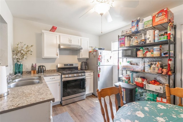 kitchen with light countertops, a sink, appliances with stainless steel finishes, under cabinet range hood, and ceiling fan