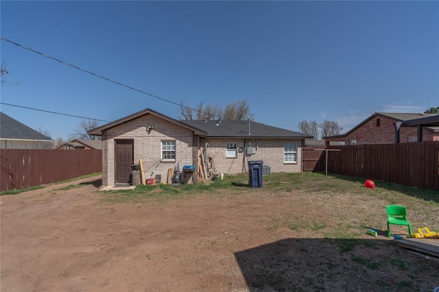 back of property with a fenced backyard and brick siding