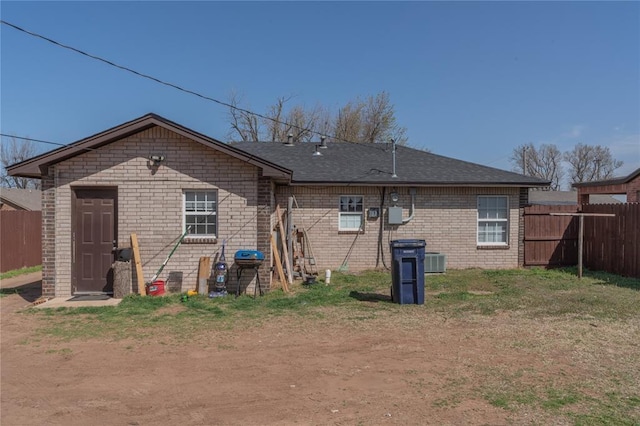 back of house with brick siding and fence