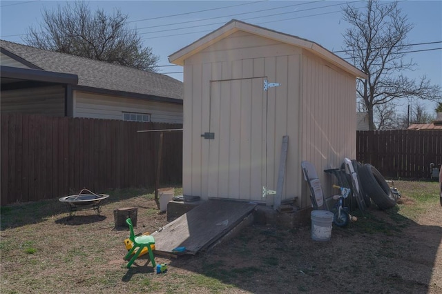 view of shed featuring a fenced backyard and a fire pit